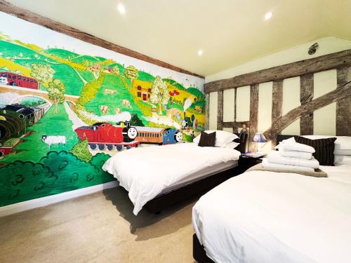 a bedroom with two beds and a mural on the wall at Cottage Farm by The Suffolk Cottage Collection in Offton