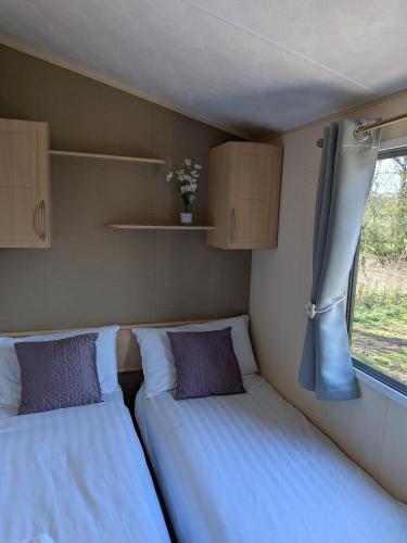 two beds in a small room with a window at 26 The Meadows in Tattershall