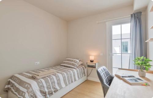 a bedroom with a bed and a desk and a window at El Rincón del Charco in Arrecife