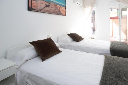 a bedroom with two beds with white sheets and brown pillows at AG Apartamentos BoiroBello 2 in Boiro