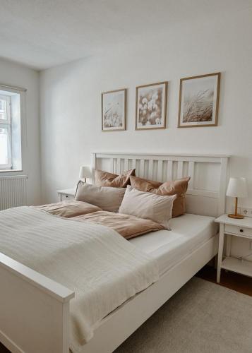a white bedroom with a large white bed with pillows at FeelingHomeApartment in Dinkelsbühl