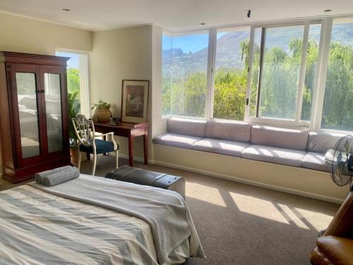 a bedroom with a bed and a couch in front of a window at Hout Bay Gem 61 Milner in Hout Bay