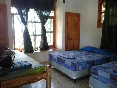 1 dormitorio con 2 camas y 2 ventanas en Villa Tortugas en Monterrico
