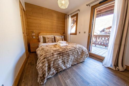a bedroom with a bed and a large window at Morzine Centre Apartment 1 min from Super M in Morzine