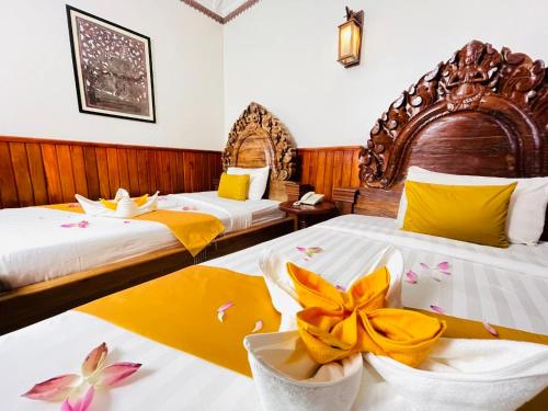 a hotel room with two beds with flowers on them at Okay 1 Villa in Siem Reap