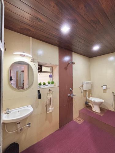a bathroom with a sink and a toilet and a mirror at Lilly Beach House in Kīhīm