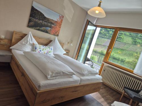a bedroom with a large bed with white sheets at Weingut Pension Gibbert-Pohl in Briedel