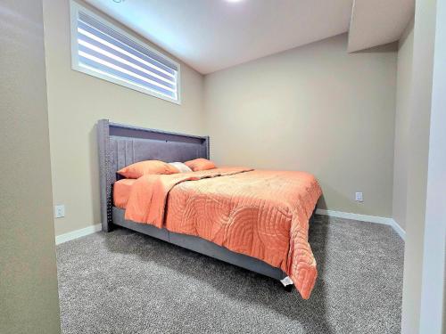 a bedroom with a bed with an orange comforter at Private, Cozy, Luxury, Spacious One Bedroom Suite in Airdrie