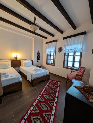 a bedroom with two beds and a red rug at Guest House Nina in Berat