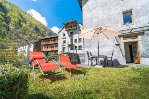 a group of chairs and an umbrella in a yard at Vallemaggia Green House in Sornico