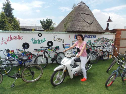 a woman standing on a scooter in front of bikes at Authentic Bicycle Tours and Backpackers in Soweto