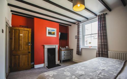 a bedroom with orange walls and a bed and a window at No.8 Accommodation in Chepstow