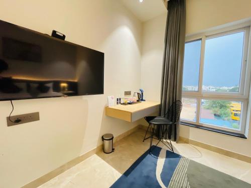 ein Zimmer mit einem Schreibtisch und einem großen Fernseher an der Wand in der Unterkunft Hotel Kyzen - Hitec city, Hyderabad in Hyderabad