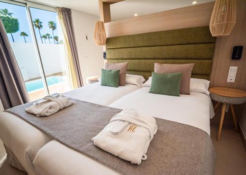 two beds in a hotel room with towels on them at HL Miraflor Suites Hotel in Playa del Ingles
