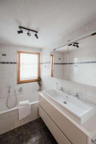 a white bathroom with a tub and a sink at Riedwohnung 2 in Lustenau