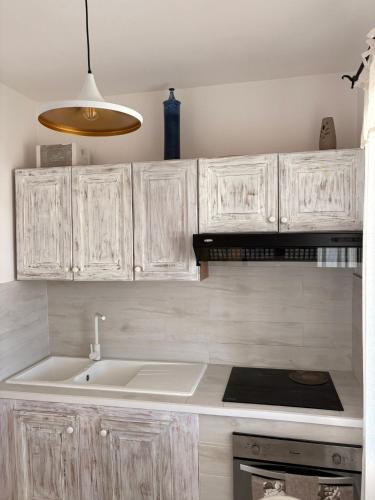 a kitchen with white cabinets and a sink at House Mia in Cala Liberotto