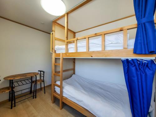 a bunk bed room with two bunk beds and a table at ゲストハウスはまなす亭 in Jōnai