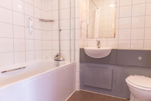 a bathroom with a sink and a tub and a toilet at Kingstown Hotel by Greene King Inns in Hull