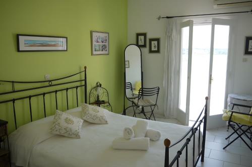 a bedroom with a bed with white sheets and a mirror at Pink Villa in Porto Heli