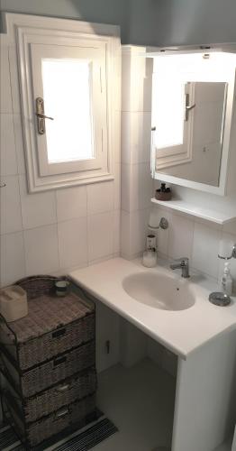 a bathroom with a sink and a mirror and a window at Pink Villa in Porto Heli