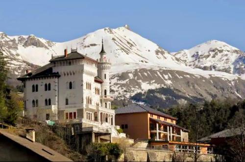 a large white building in front of a snow covered mountain at Duplex equipped for 6 people in Jausiers