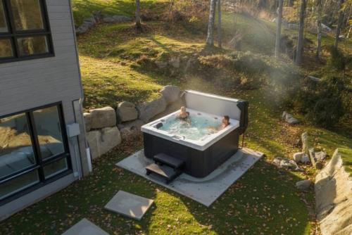 two people in a bath tub in a backyard at Spa & Sauna Pool Table & Game Room - Le Perche in Brownsburg