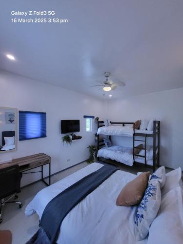 a bedroom with two beds and a desk and a tv at The beach house, Baroro Beachfront Villa in Bacnotan