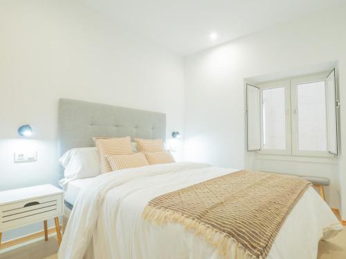 a white bedroom with a large bed and a window at YBH Villa Lara in Villanueva de Arosa
