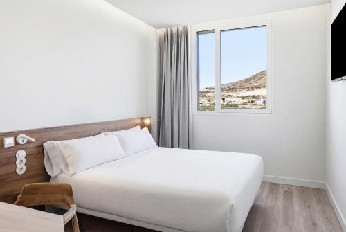 a white bedroom with a bed and a window at B&B HOTEL Cieza in Cieza