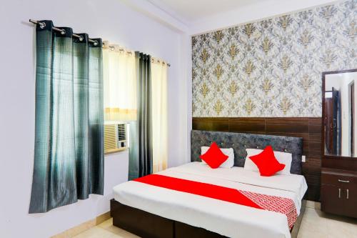 a bedroom with a bed with red pillows at Hotel O Raama in Lucknow