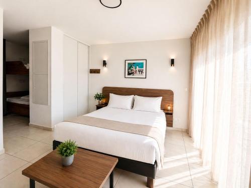 a bedroom with a large bed and a table at Nemea Appart Hotel Les Hauts de Milady Biarritz in Biarritz