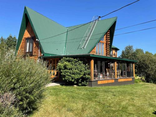 a wooden house with a green roof on a yard at Spa Swimming Pool & Nature - Chalet rang 3 in Roberval