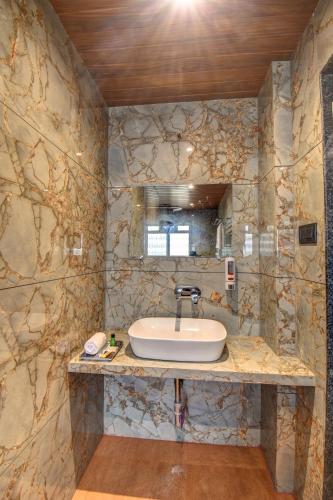 ein Badezimmer mit Waschbecken und einer Steinwand in der Unterkunft Holiday Plus in Panchgani