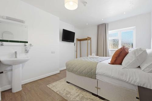 a white bedroom with a bed and a sink at The Forest- Fernwood in Cambridge