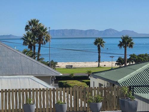 a view of the ocean from a fence with palm trees at Charla on the Beach in Gordonʼs Bay