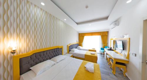 a bedroom with two beds and a desk and a mirror at Yade Luxe Hotel in Marmaris