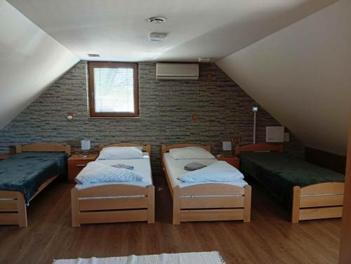 a attic room with three beds and a brick wall at Penzión Kállai a Vináreň in Fiľakovo