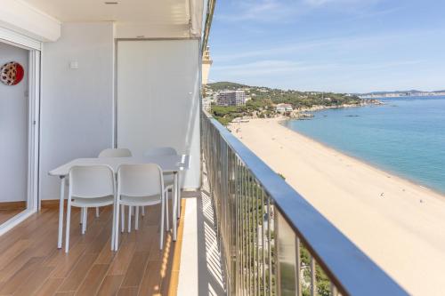 a balcony with a table and chairs and a beach at Pis Embaixador - 1a línea de mar in Platja d'Aro