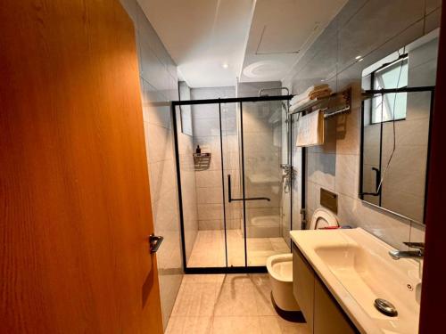 a bathroom with a shower and a toilet and a sink at Masaki Cozy Stay in Dar es Salaam