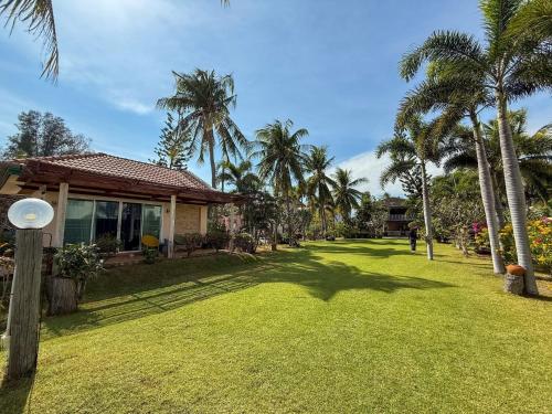 a yard with palm trees and a house at The Rich Instantly Home in Sathani Huai Yang