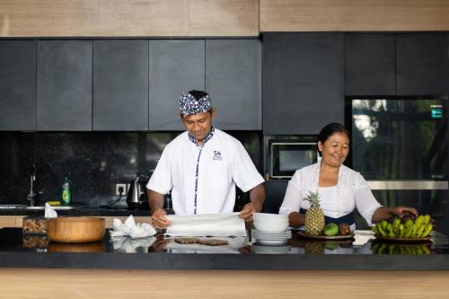 a man and a woman preparing food in a kitchen at Villa Kalisha - Romantic, Seclusion in the heart of Nature in Tegalalang