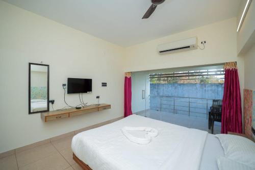 a bedroom with a white bed and a television at La PAVI RESORT in Auroville