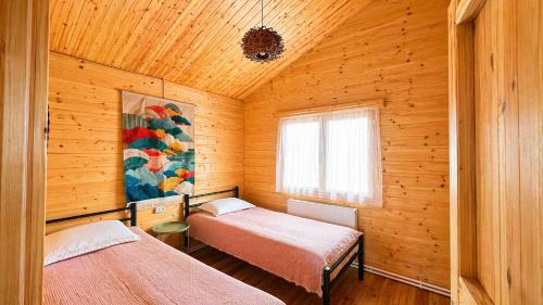 a bedroom with two beds in a wooden cabin at chemtan cottages in Dushetʼi