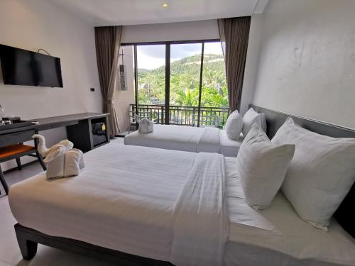 a bedroom with two beds and a desk and a window at Maehaad Bay Resort - SHA Plus in Mae Haad
