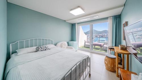 a bedroom with a bed and a large window at Tongyeong Present Gamsung Pension in Tongyeong