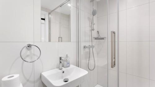a white bathroom with a shower and a sink at Pavement Cottage in Ambleside