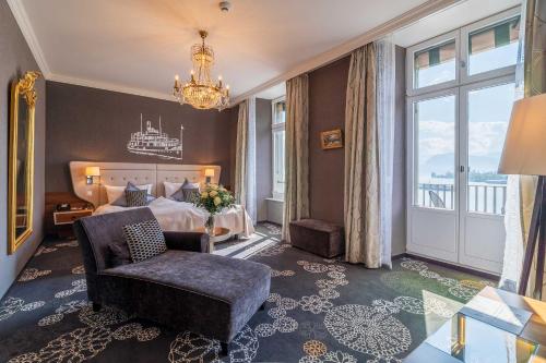 a bedroom with a bed and a chair and a chandelier at Hotel Schweizerhof Luzern in Lucerne