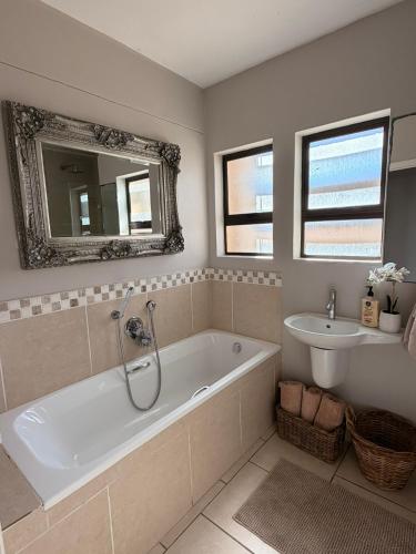 a bathroom with a tub and a sink and a mirror at Klein paradys Jeffreys bay in Jeffreys Bay