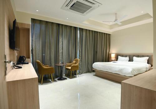 a hotel room with a bed and a table and chairs at hotel arya inn in Prayagraj