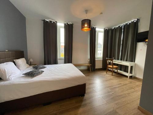 a bedroom with a bed and a desk and windows at Le Cecil in Liège